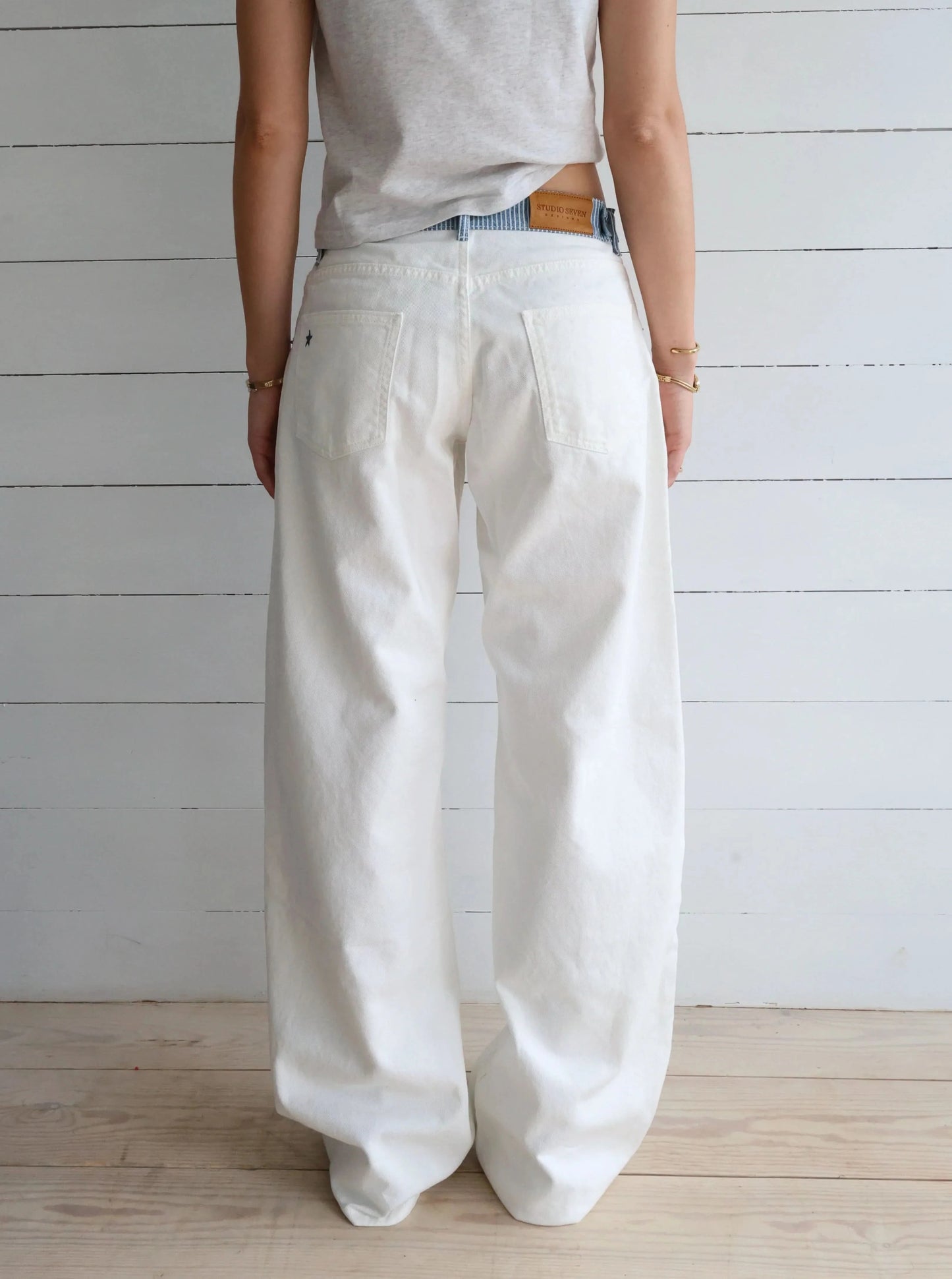 White denim jeans pocket detail with blue striped waistband and brass hardware