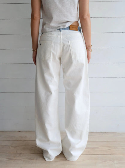 White denim jeans pocket detail with blue striped waistband and brass hardware
