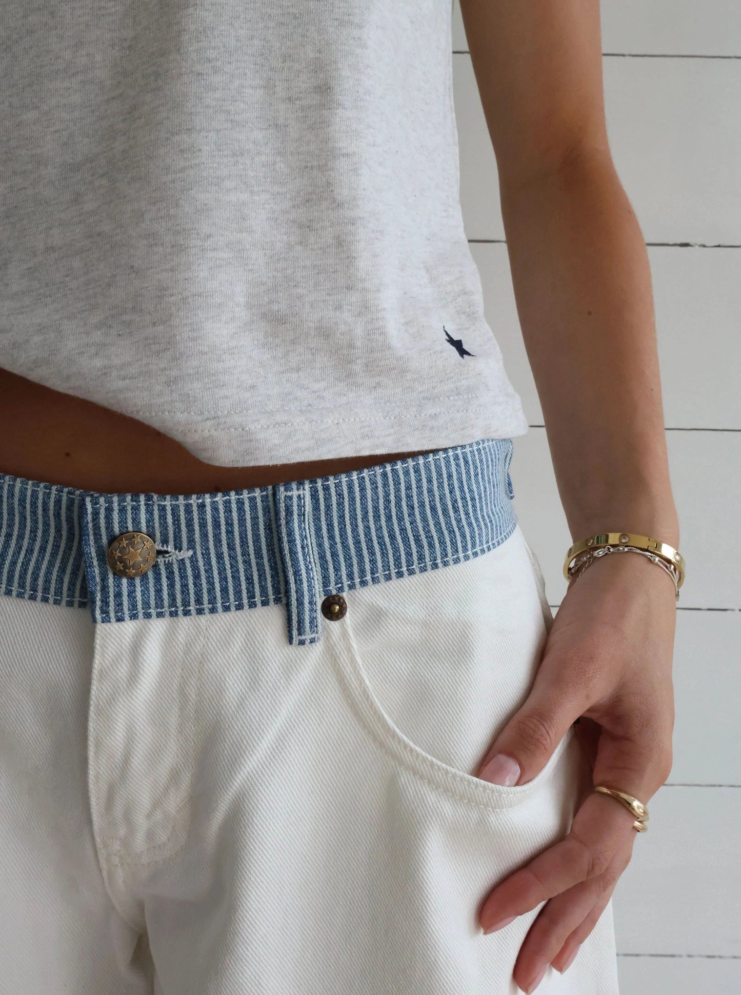 White denim jeans pocket detail with blue striped waistband and brass hardware