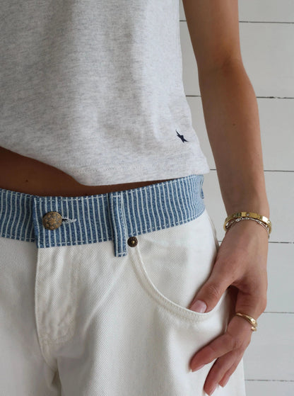 White denim jeans pocket detail with blue striped waistband and brass hardware