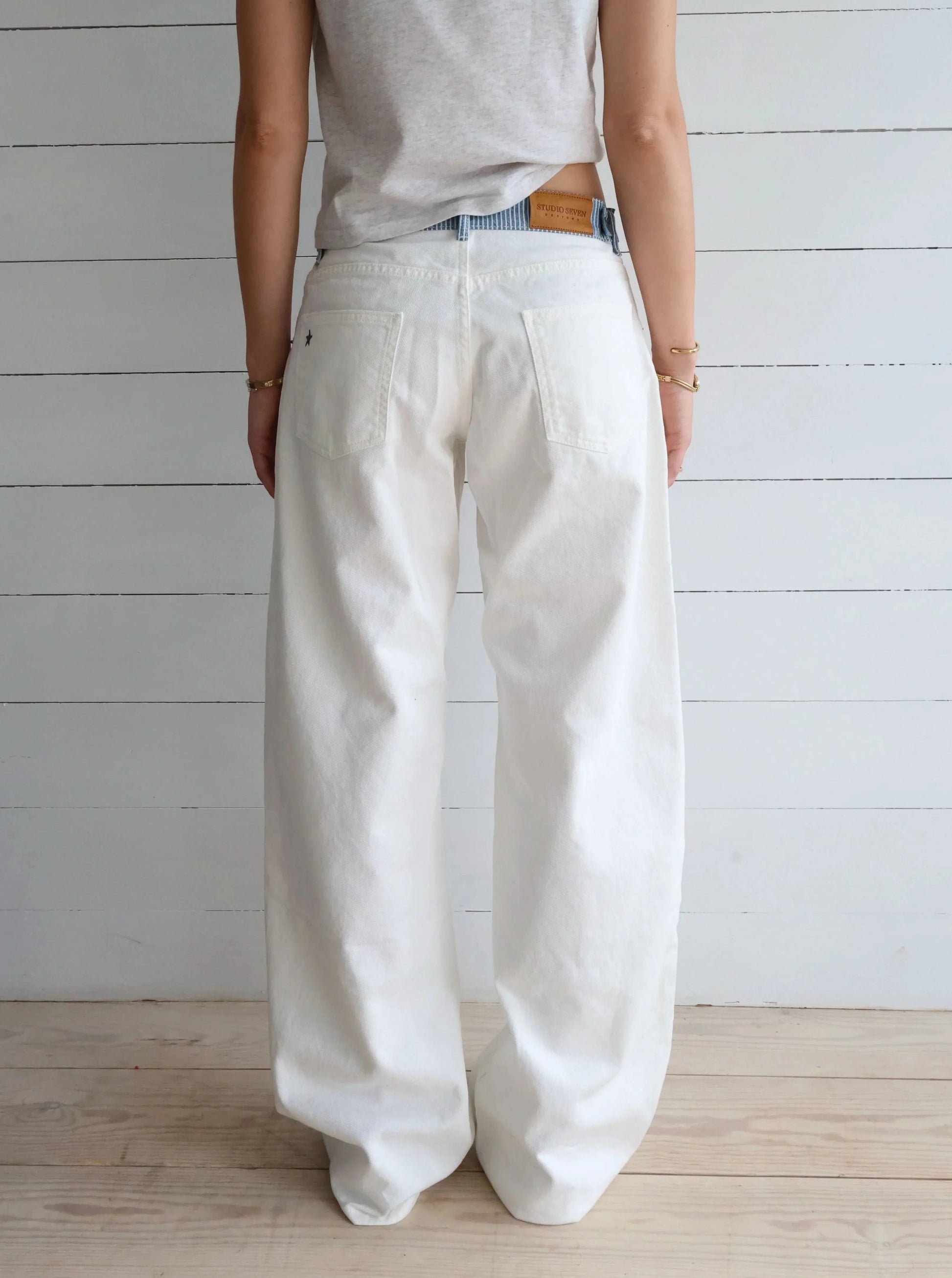Back view of white denim jeans with leather patch label and rear pockets
