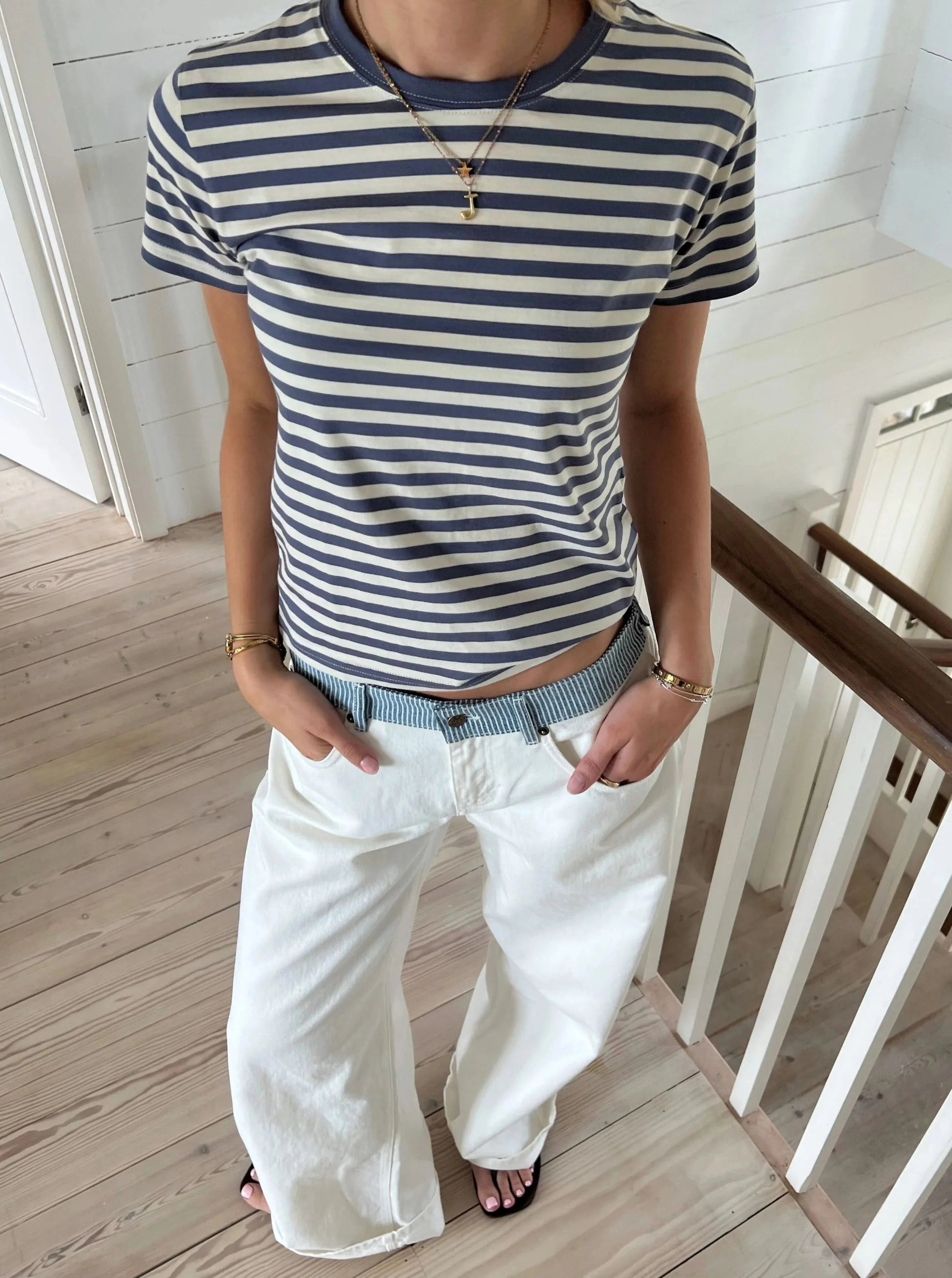 White denim jeans styled with navy striped shirt, full body front view