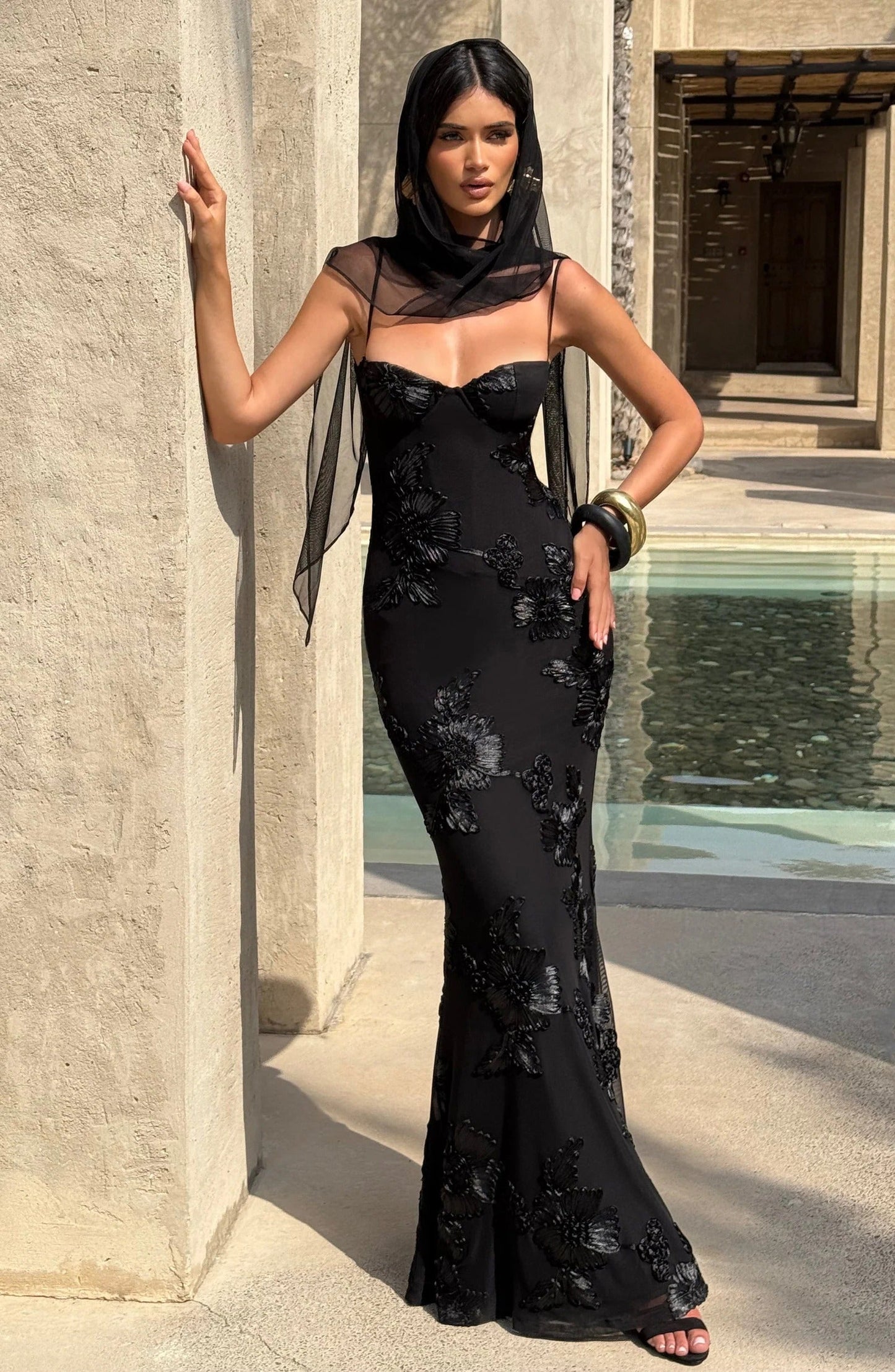 Black floral corset maxi dress worn with sheer overlay and poolside setting