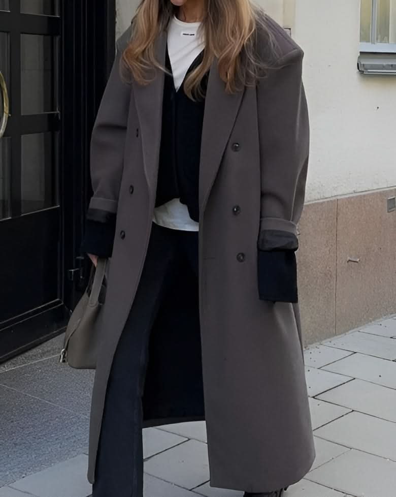 Gray double-breasted long coat with notch lapels and rolled cuffs worn over black and white layers