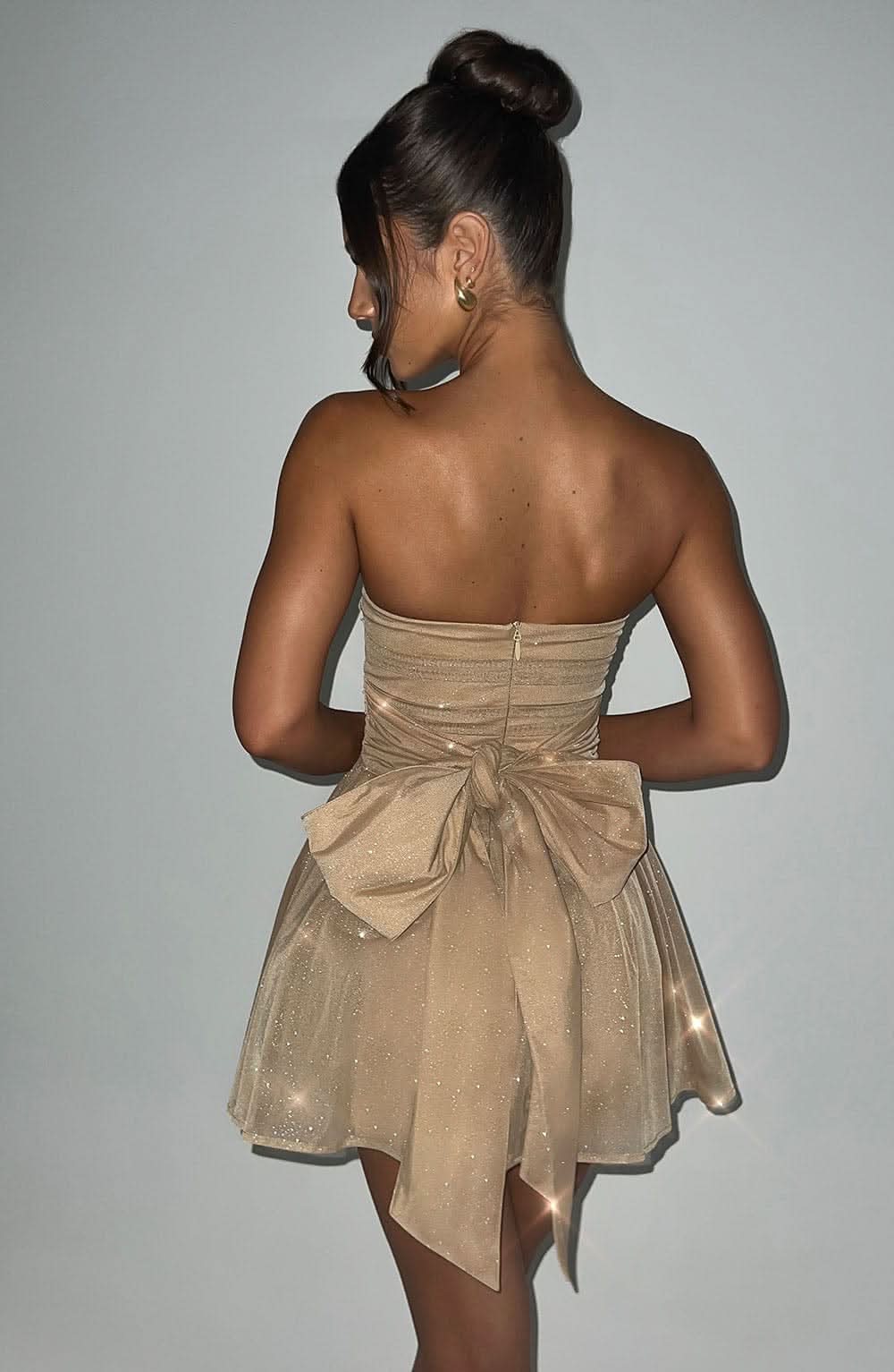 Back view of champagne glitter mini dress with bow detail and zipper