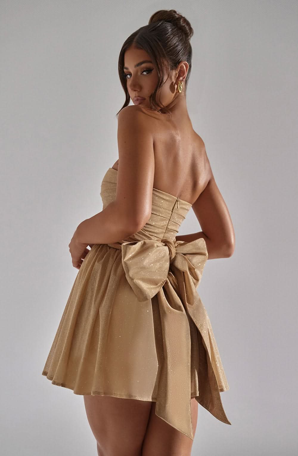 Back view gold sequin mini dress with large bow tie detail