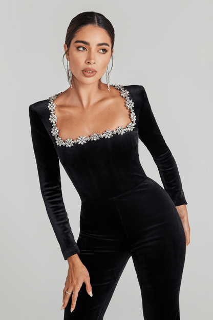 Close-up of black velvet jumpsuit neckline with rhinestone flower trim detail
