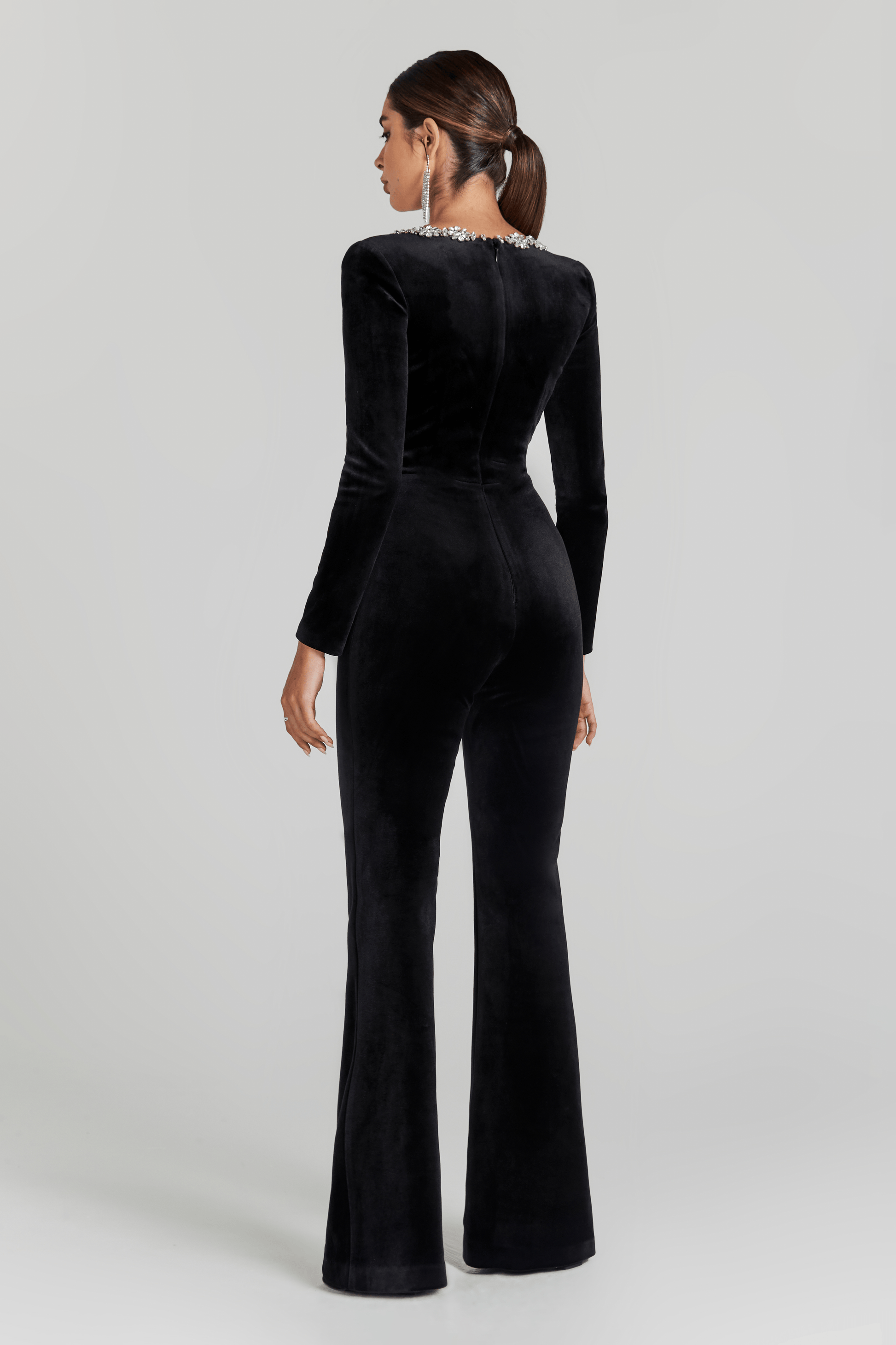 Back view of black velvet jumpsuit with long sleeves and flared pants