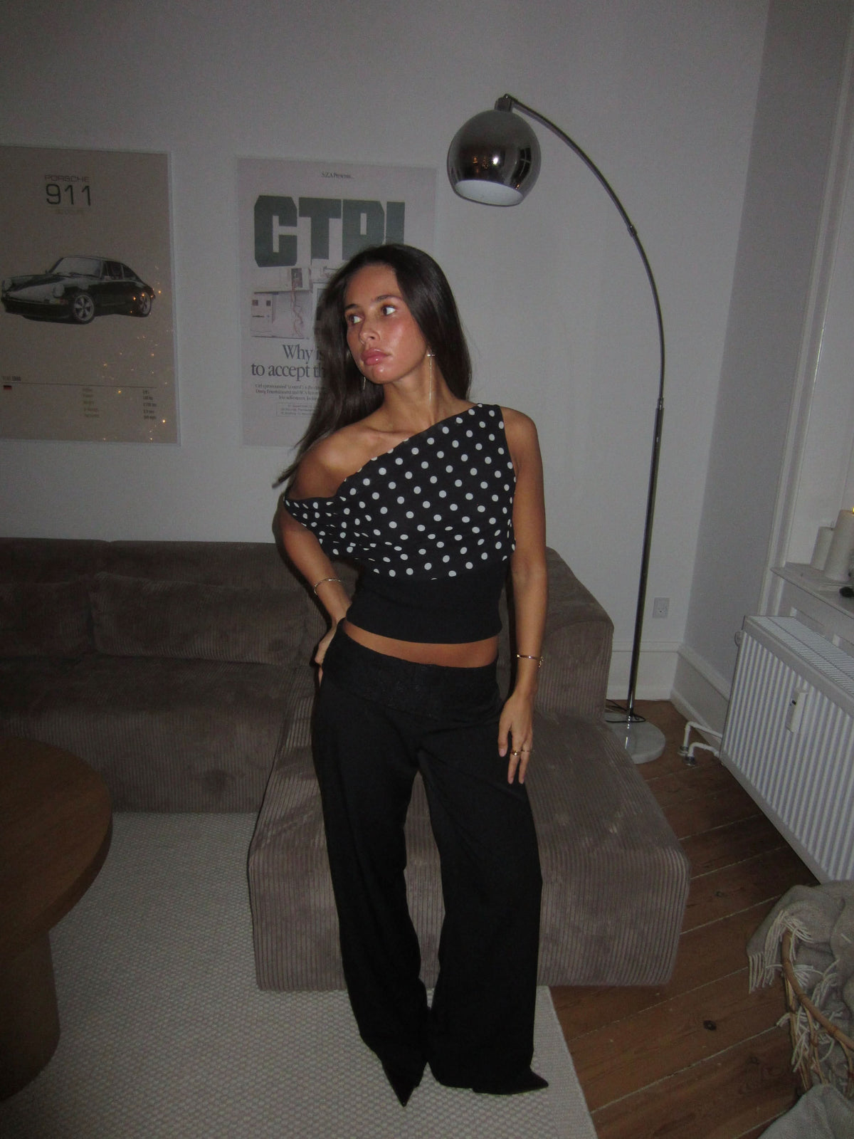 Black and white polka dot one-shoulder crop top with ribbed black waistband