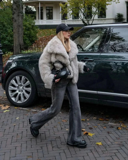 Beige fur coat with wide collar paired with dark jeans and black handbag