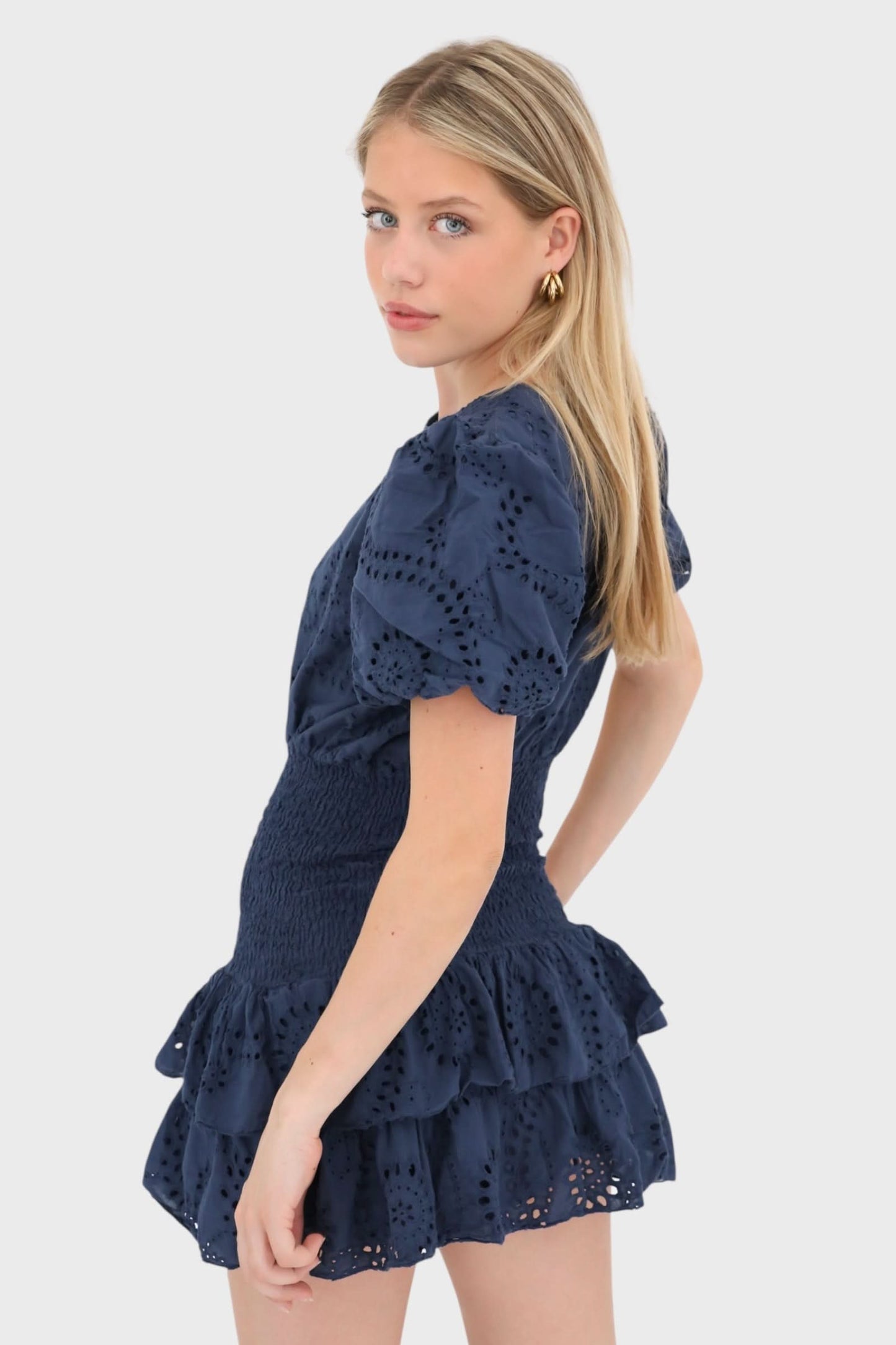 Side view of navy perforated mini dress with tiered ruffle skirt