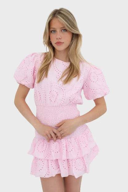 Pink eyelet mini dress with short puffed sleeves and smocked waist detail