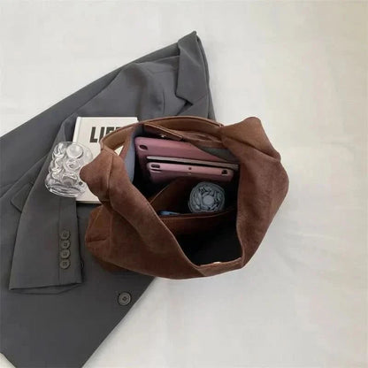 Brown suede tote bag packed with phone, wallet, and daily essentials
