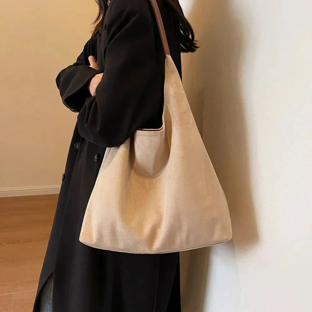 Cream suede tote bag worn as shoulder bag with black blazer