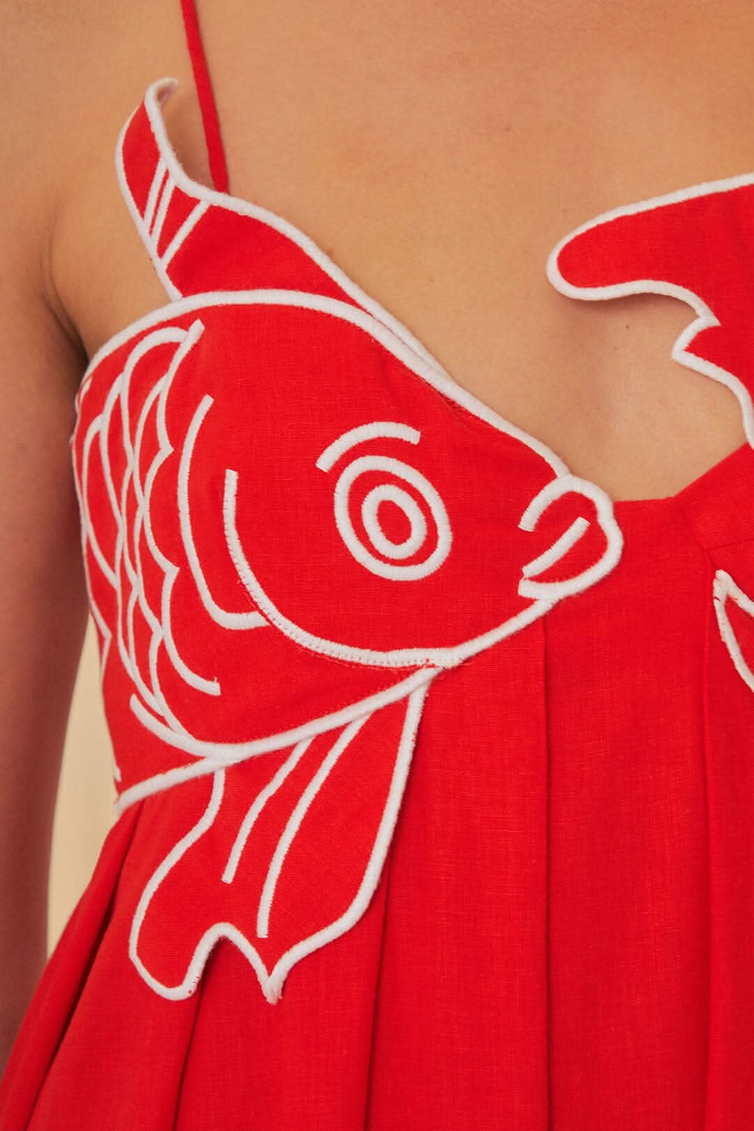 Detail of red maxi dress chest with embroidered fish motif