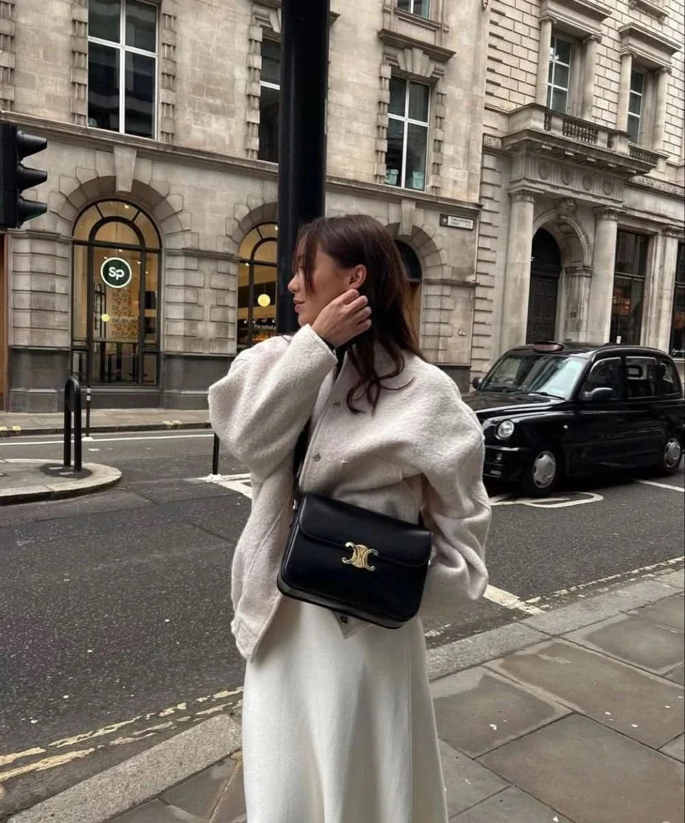 Cream wool bomber jacket styled with white midi skirt on city street