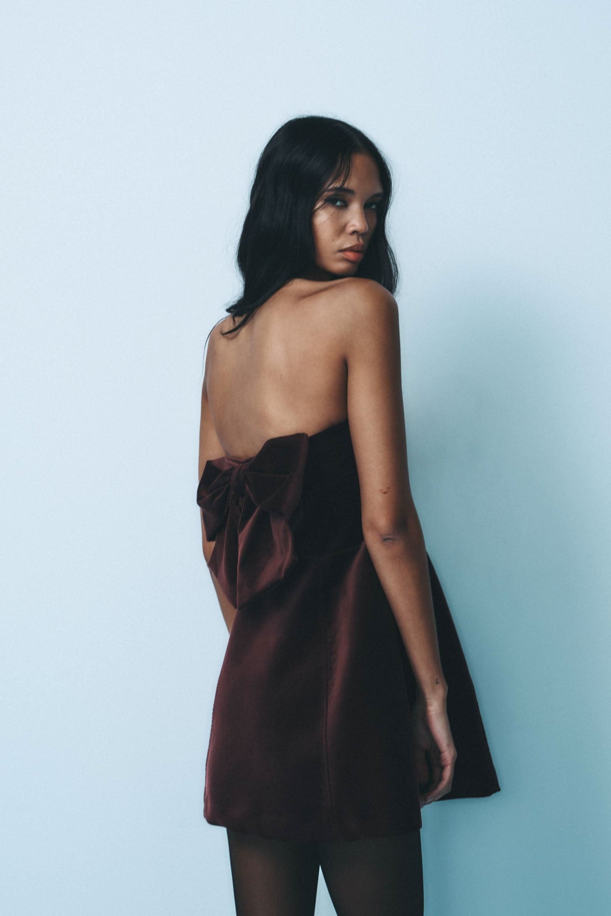Back view of burgundy velvet mini dress showing bow detail