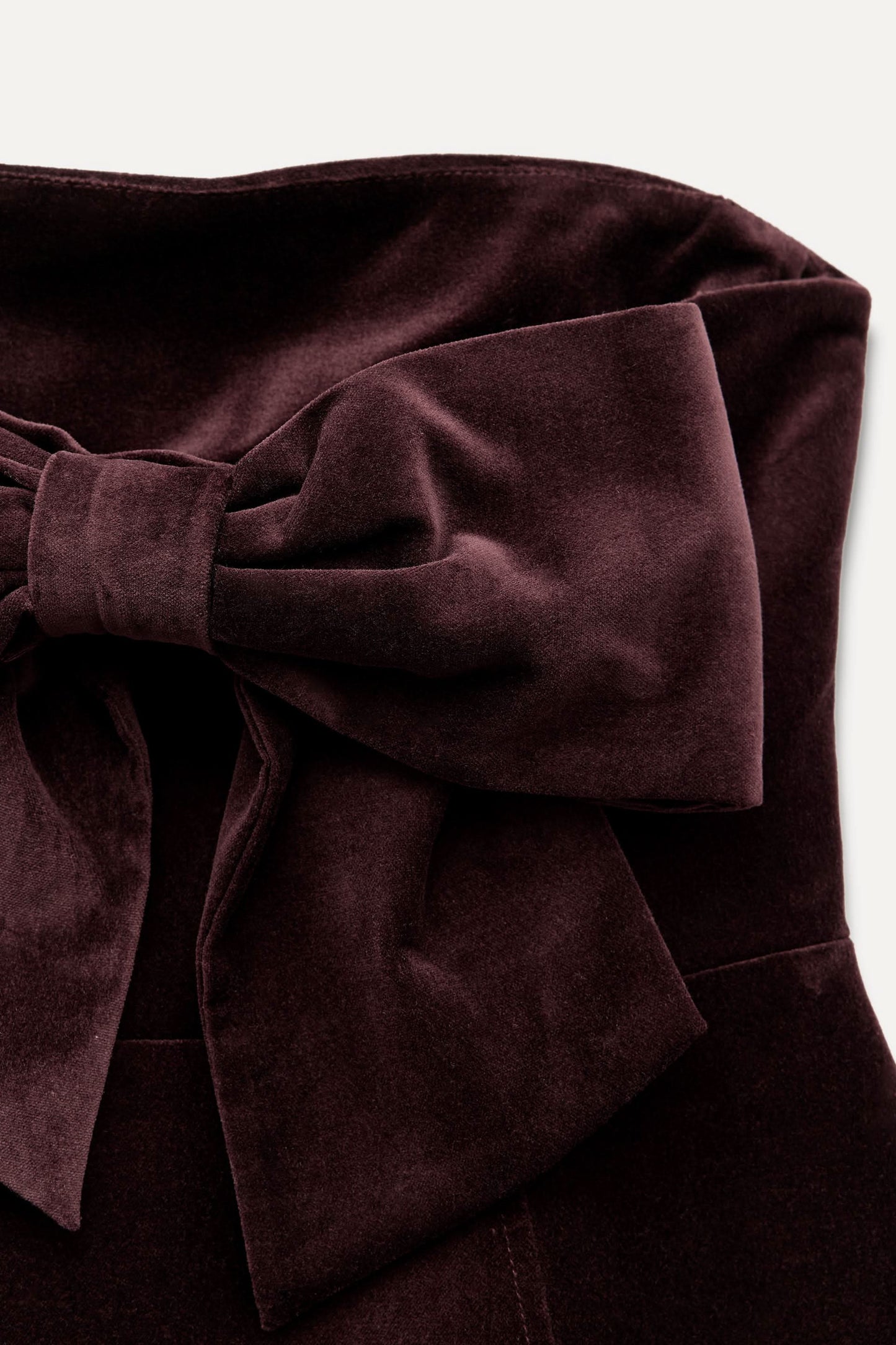 Close-up of burgundy velvet bow detail on mini dress