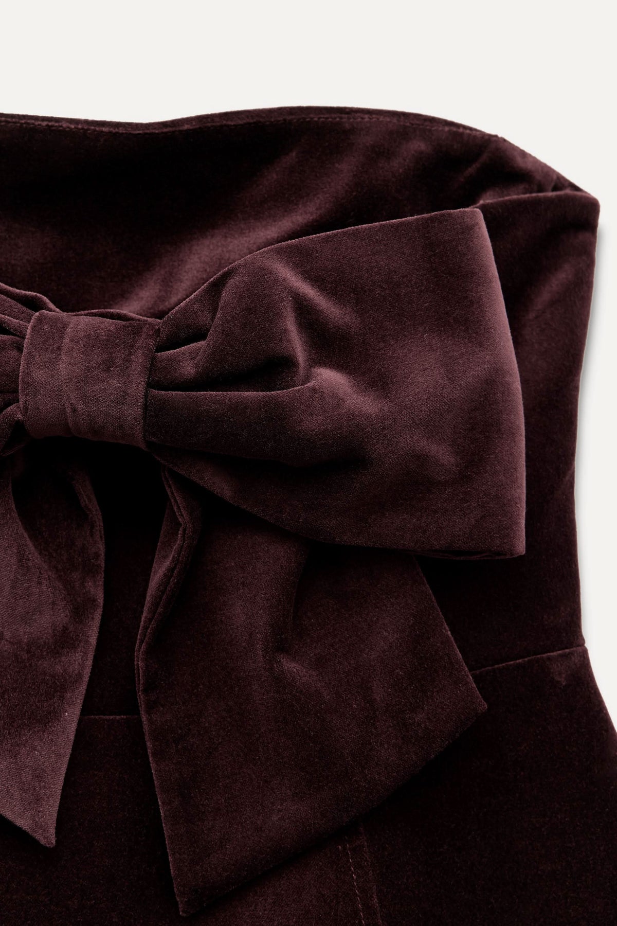 Close-up of burgundy velvet bow detail on mini dress