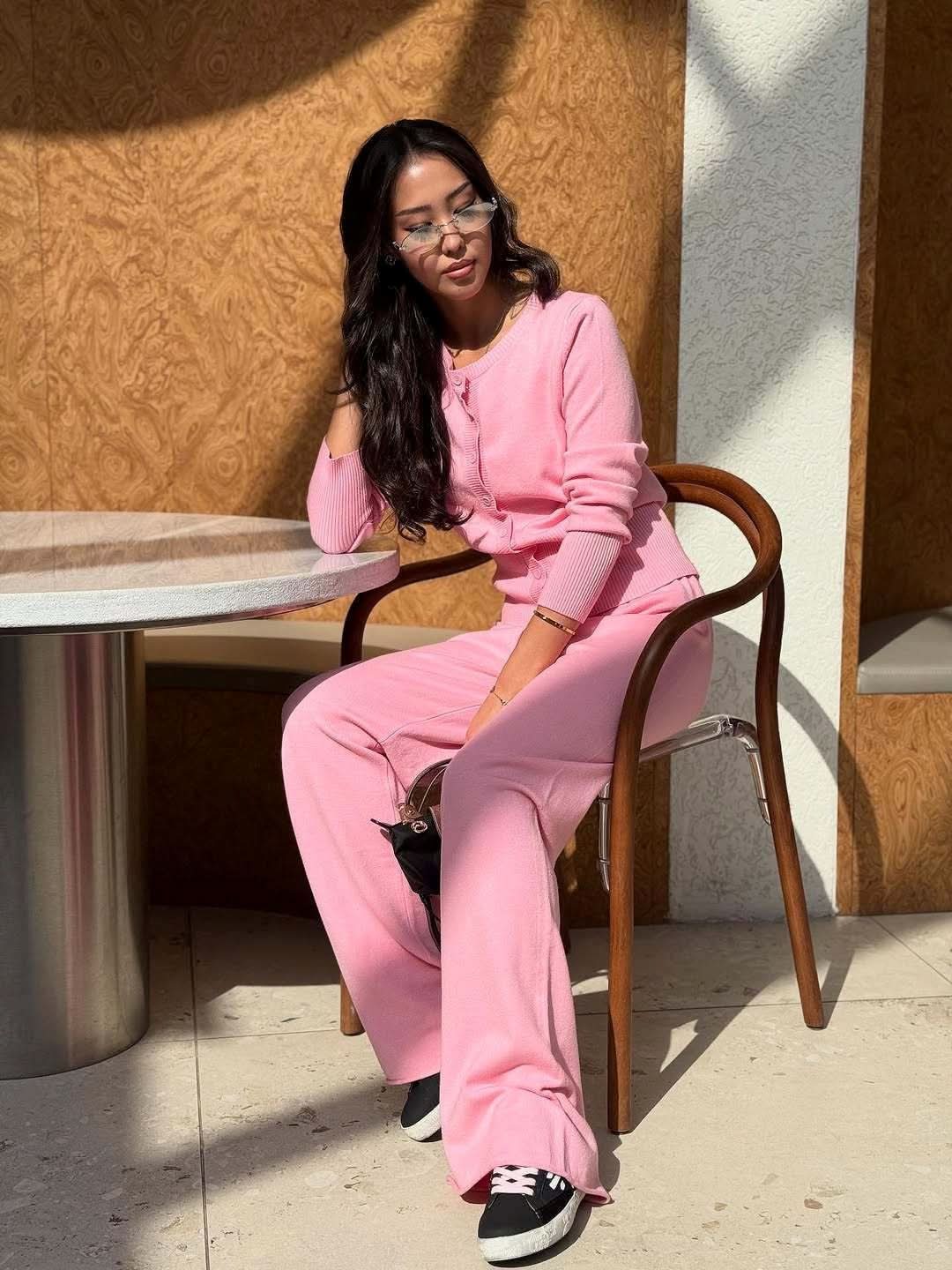 Pink button-up ribbed cardigan with coordinating knit pants, seated pose