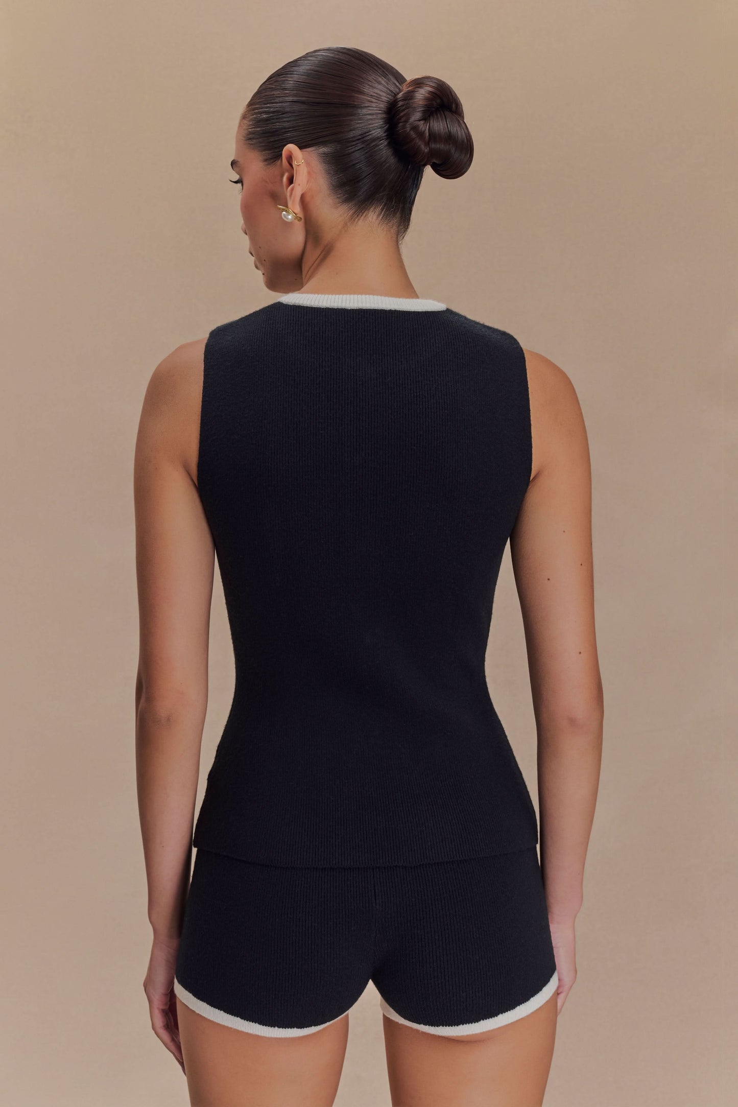 Back view of sleeveless black knit tank with white crew neckline