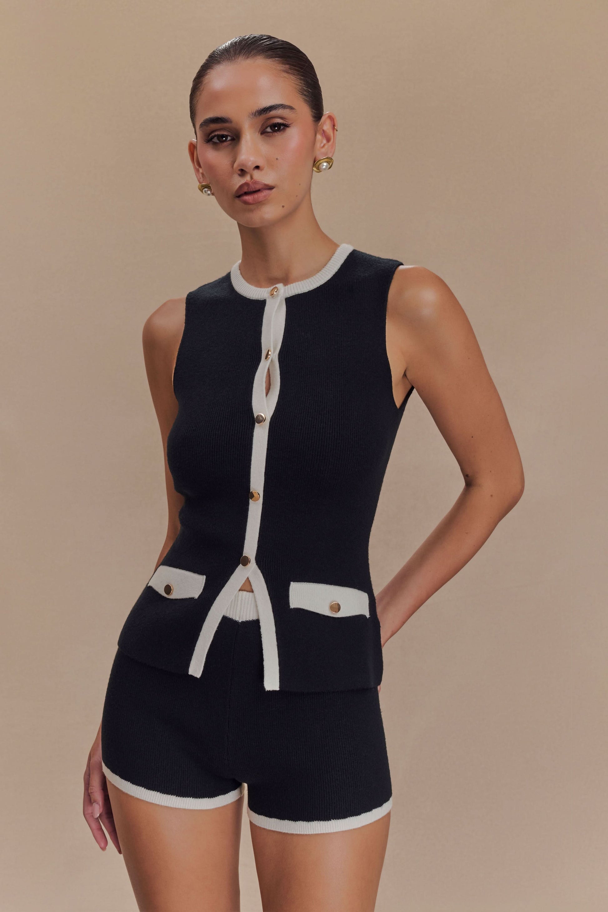 Black ribbed knit vest with white trim and button front closure