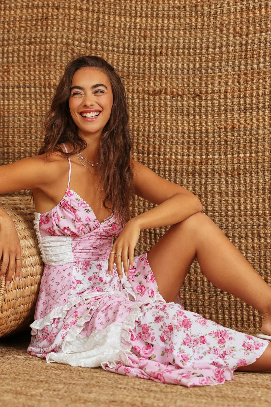 Seated view of pink floral maxi dress with white ruffle layers and wrap waist