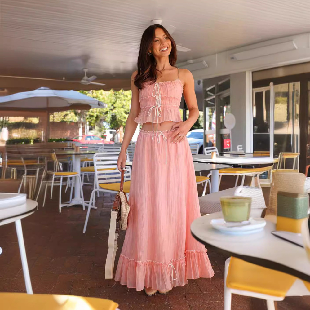 Pink pleated maxi skirt set with ruched crop top and ruffled hem worn at outdoor venue