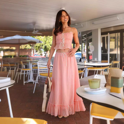 Pink pleated maxi skirt set with ruched crop top and ruffled hem worn at outdoor venue