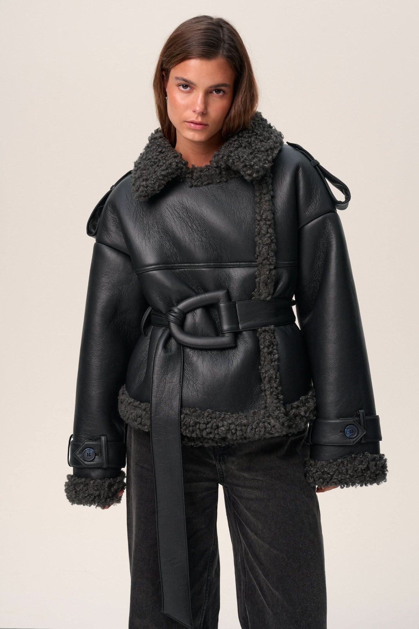Black leather cropped coat with charcoal fleece lining, belted silhouette, close-up