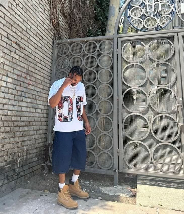 White 90s graphic jersey tee styled on model with navy shorts and boots