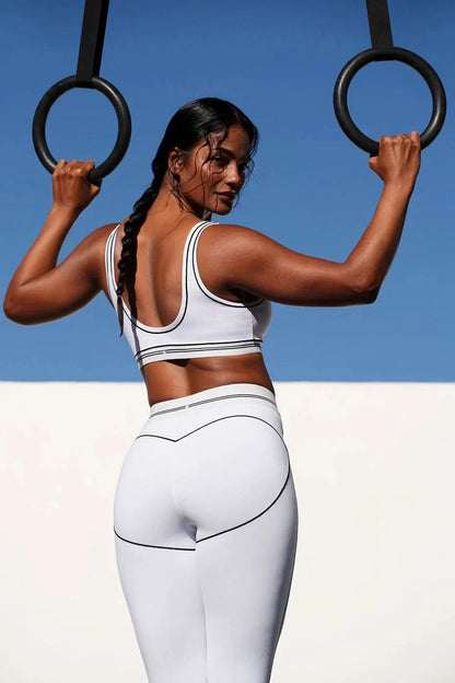 White shorts and sports bra set with contrast trim during stretching pose