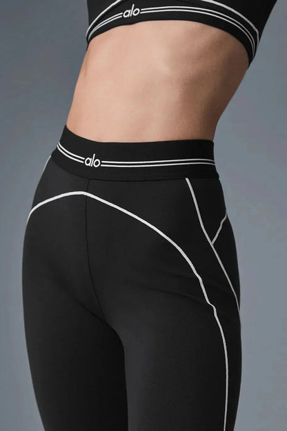 Close-up of black sports bra and shorts with white contrast trim and striped bands