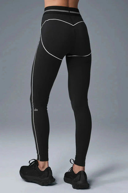 Close-up of black sports bra and shorts with white contrast trim and striped bands