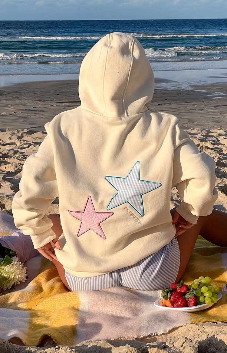 Rear detail of cream hoodie with contrasting star design and drawstring hood visible
