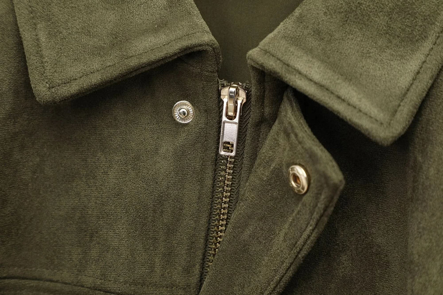Close-up of silver metal zipper and snap button on olive suede jacket