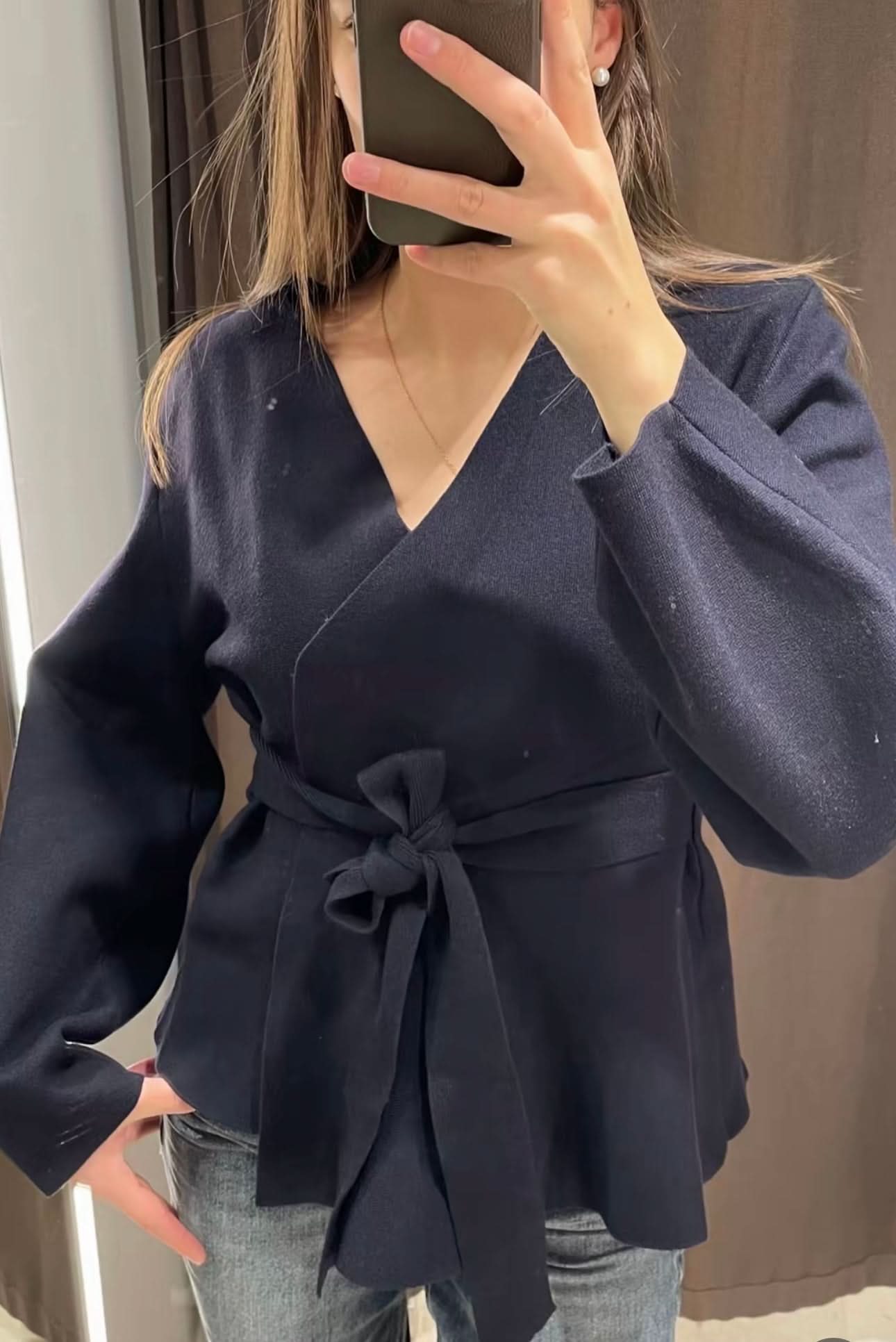 Close-up of navy cardigan tie belt detail with puffed sleeves