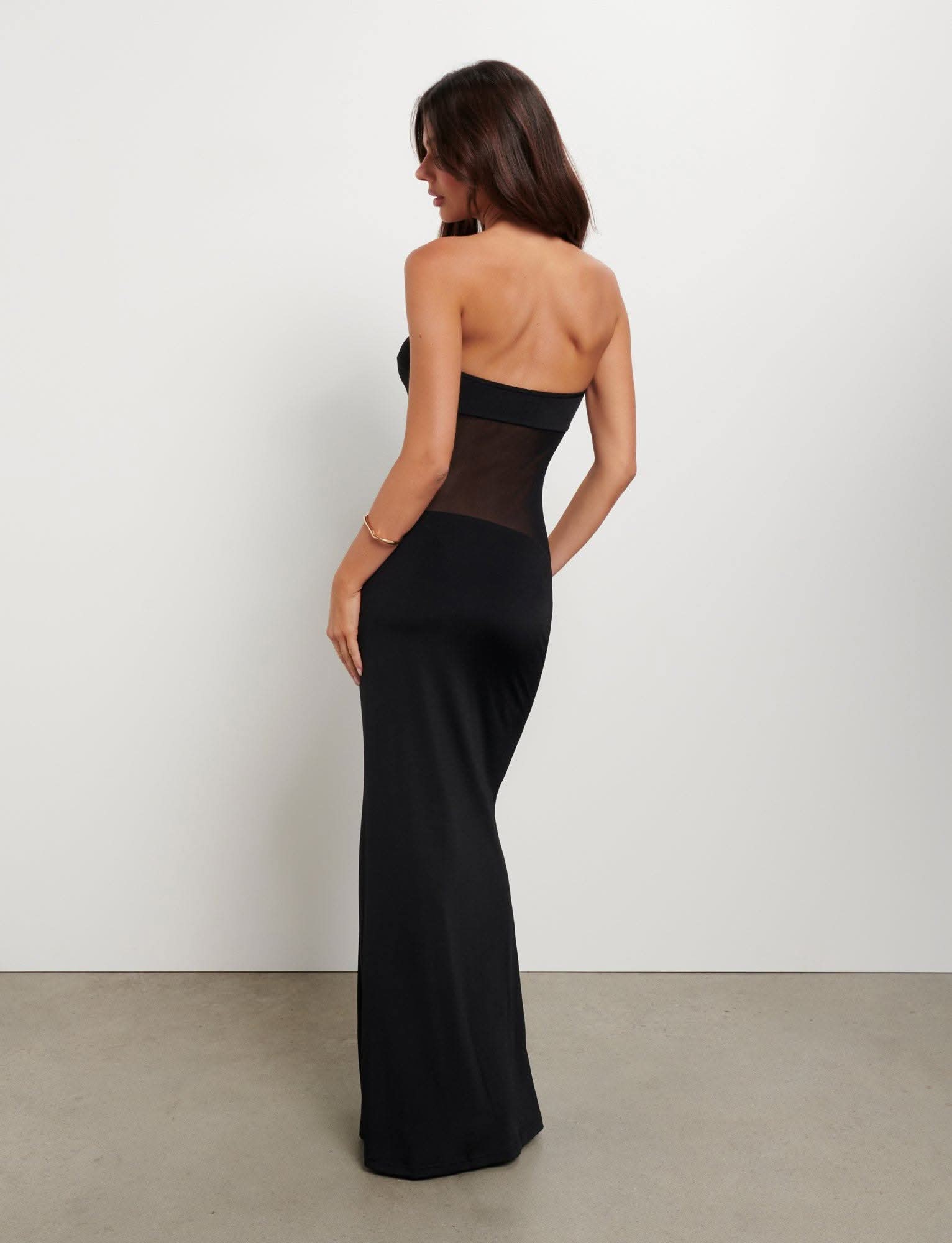 Back view of black strapless maxi dress with sheer midsection detail