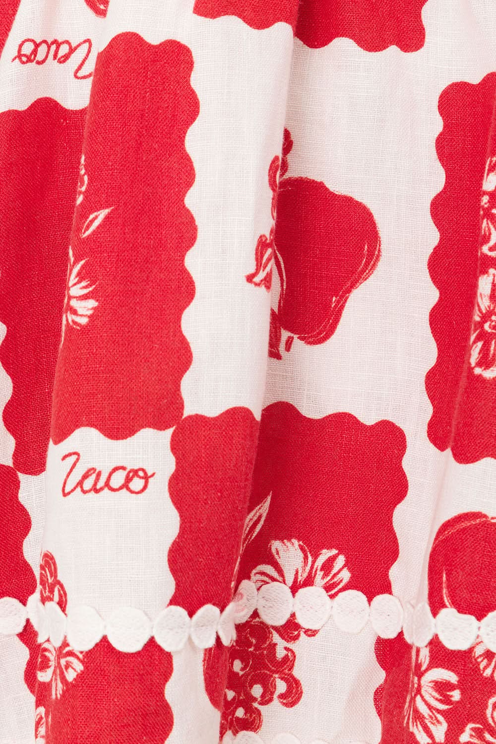 Close-up of red and white floral fabric with scalloped pearl trim detail