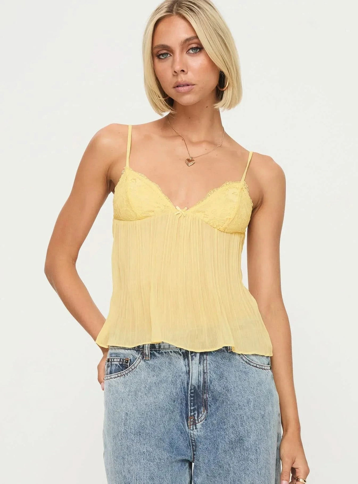 Front view of pale yellow pleated top with delicate lace bust detail