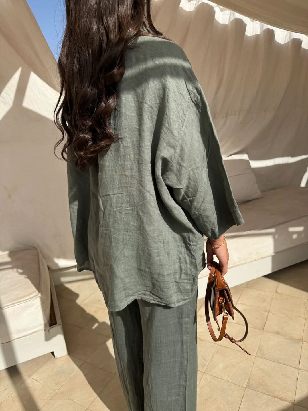 Back view of sage green linen shirt displaying natural fabric texture and drape