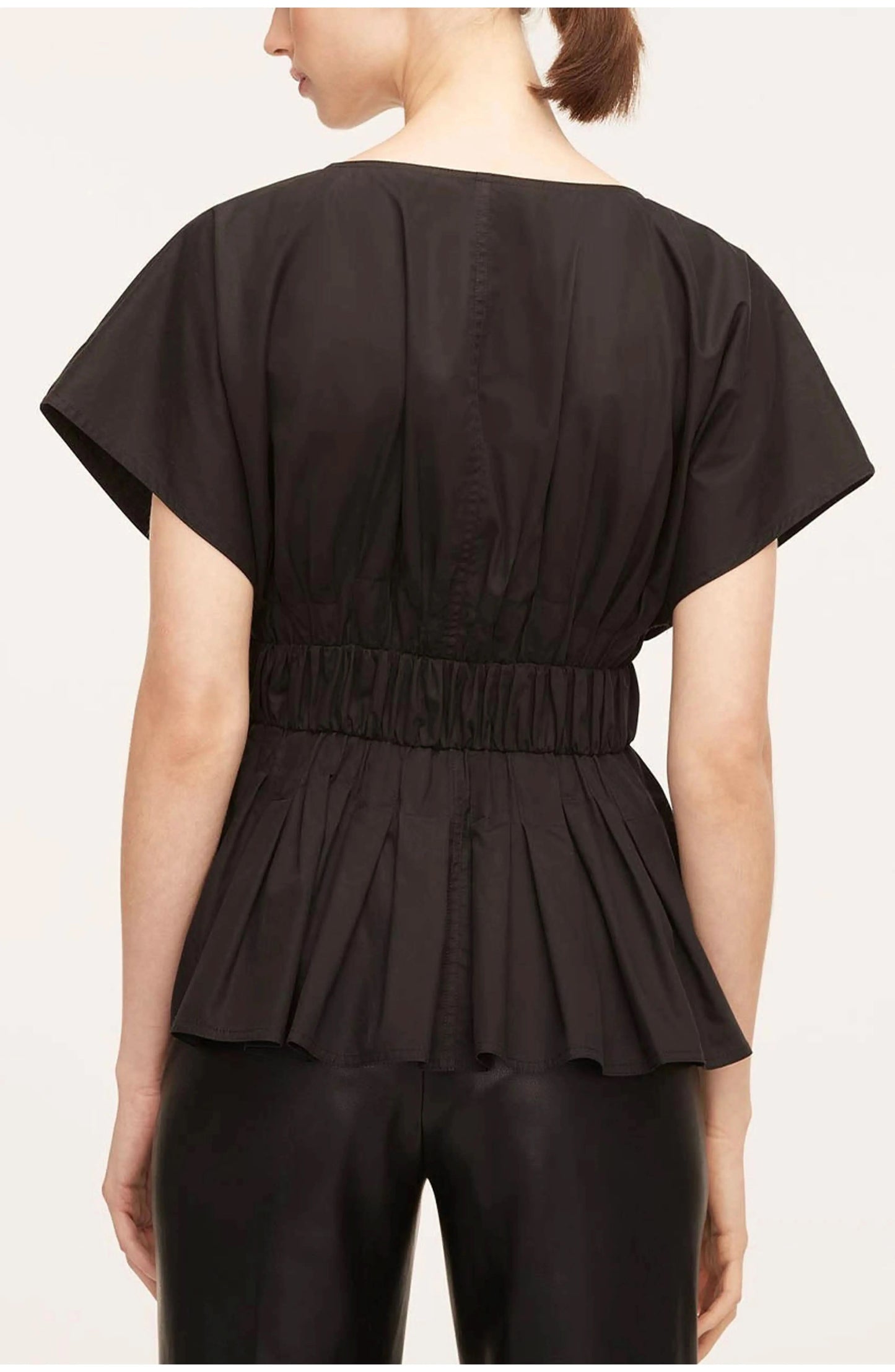 Back view of black belted blouse with center seaming and structured pleated design