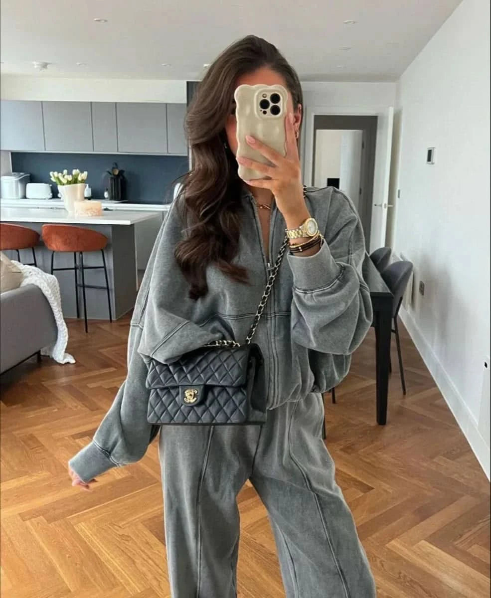 Gray comfy tracksuit with zip-up jacket and relaxed pants, styled with chain bag
