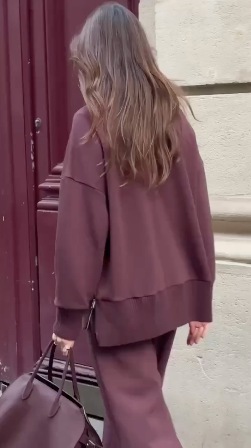 Rear angle of burgundy knit sweater and matching wide-leg trousers with bag
