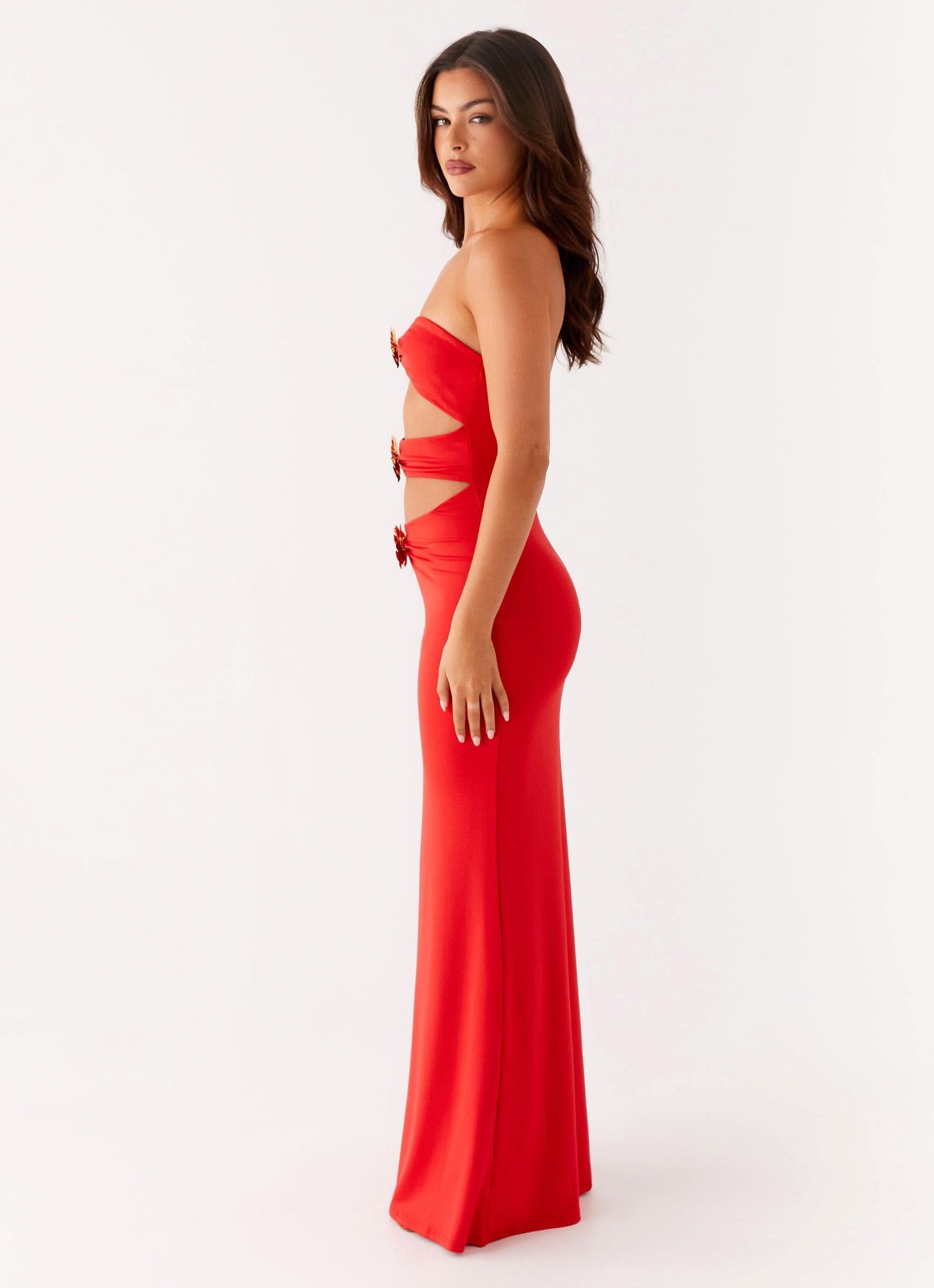 Side view of red evening gown with strapless design and gold embellished side cutouts