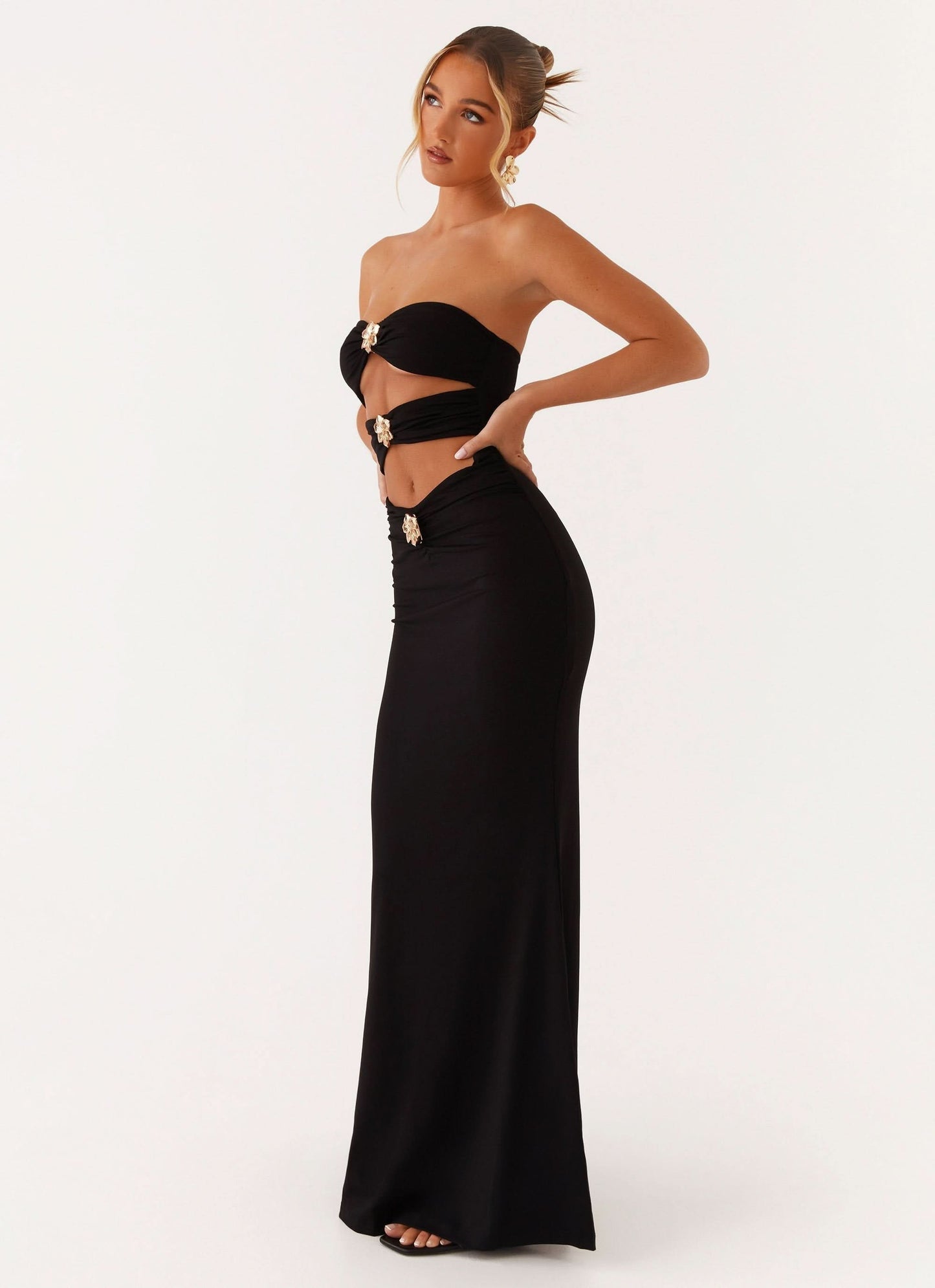 Black strapless maxi dress with gold ornament cutout details and fitted silhouette