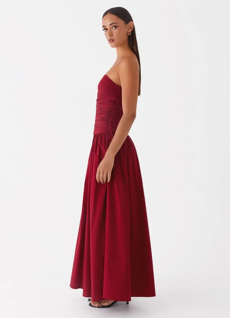 Burgundy strapless maxi dress with ruched torso and full skirt, side view profile