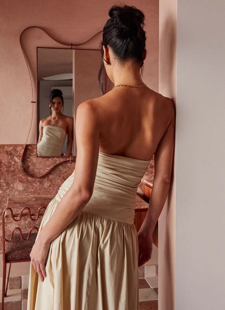Back view of cream strapless maxi dress showing open back design