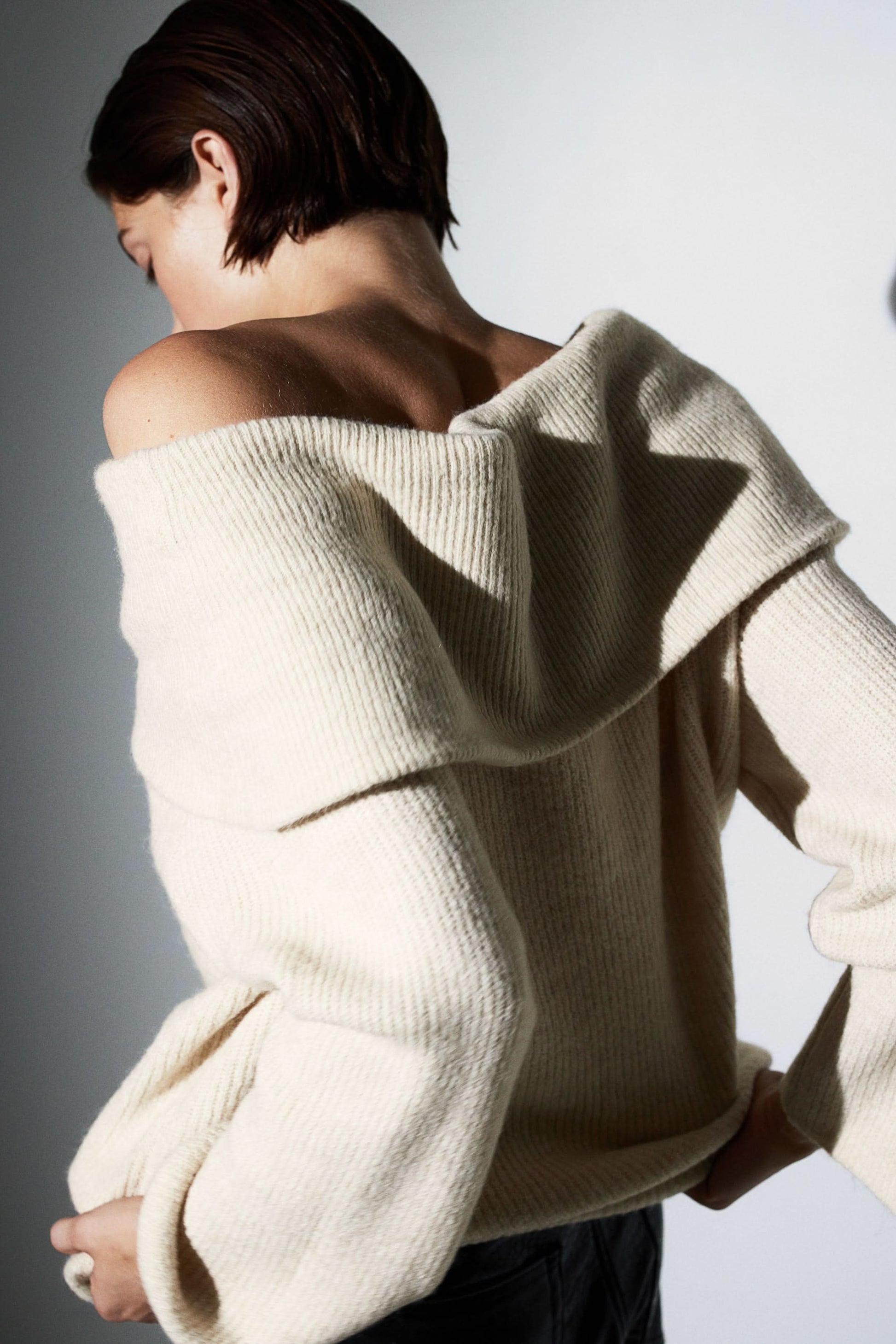 Back view of cream off-shoulder sweater showing drape detail
