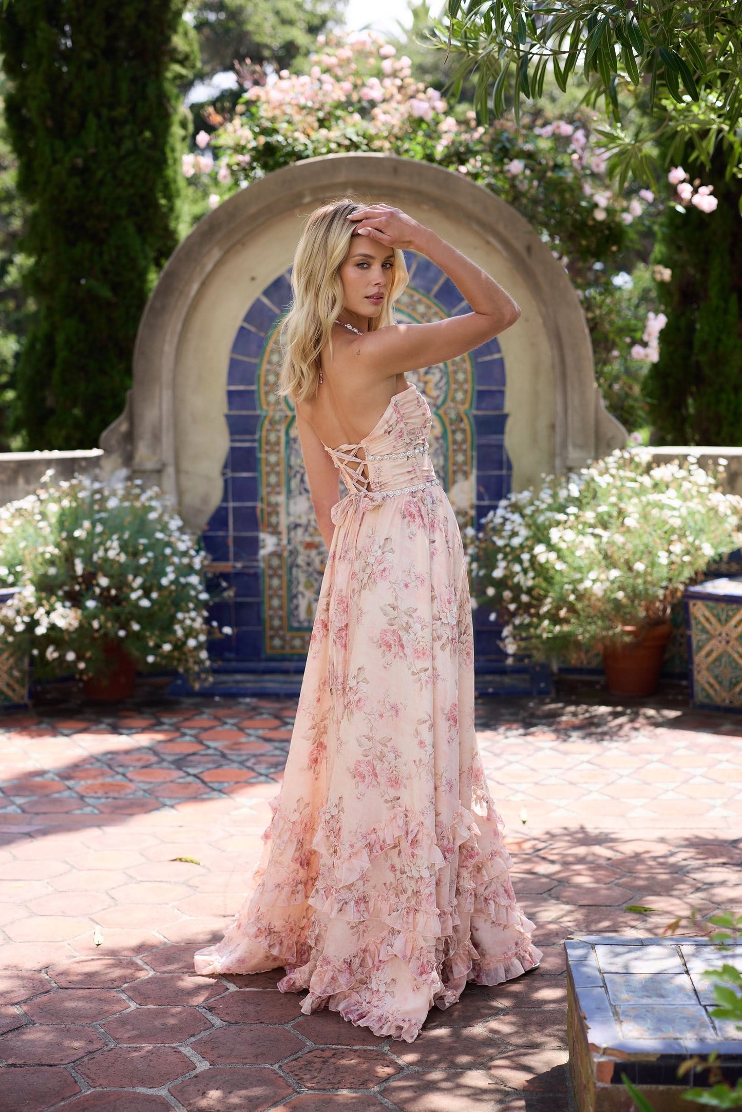 Blush pink floral halter maxi dress with beaded waist and layered ruffled hem in garden setting